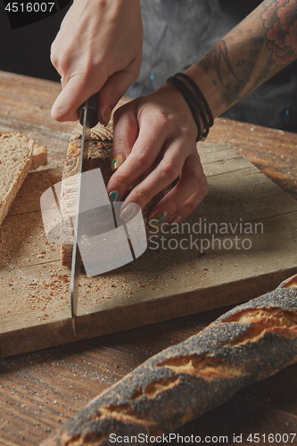 Image of Woman\'s hands cut fresh bread