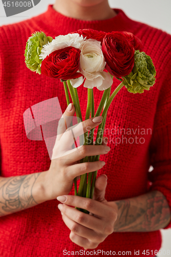 Image of Young girl in a red sweater holding a bouquet of fresh flowers.