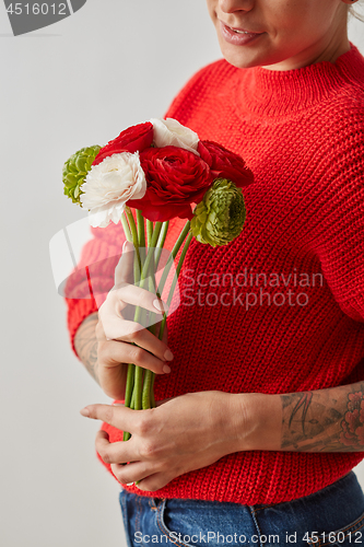 Image of A fresh bouquet of flowers Ranunculus in the hands of a woman on a gray background. Card