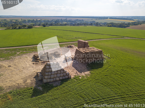 Image of Green field with large haystacks and tractor on a sunny day. Aerial view from the drone