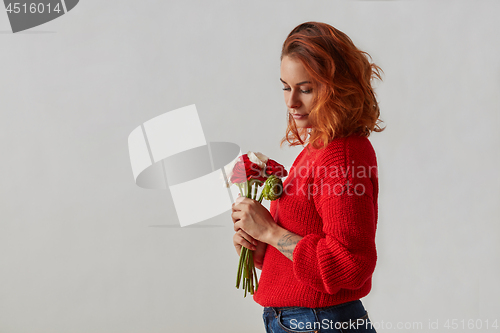 Image of Attractive woman with a bouquet of beautiful flowers in her hands on a gray background