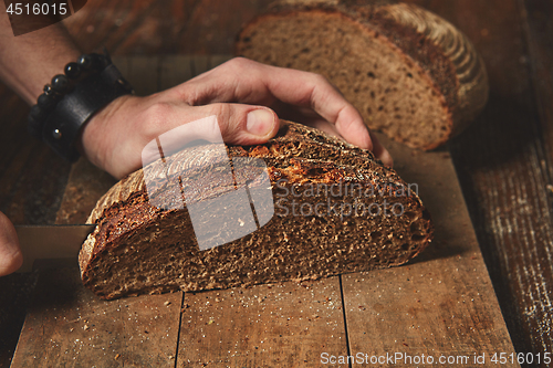 Image of organic bread cut a man\'s hands
