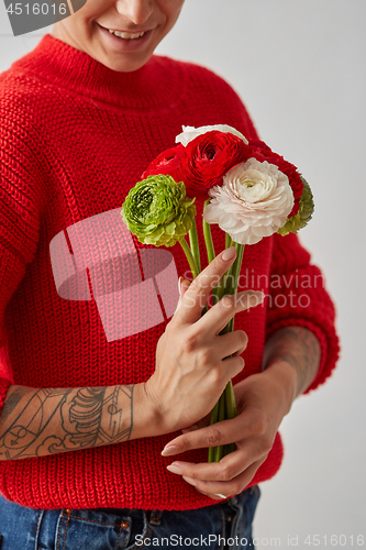 Image of Beautiful girl in a red sweater with flowers in hands on a white background