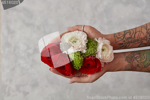 Image of girl with a tattoo on her hands holding a bouquet of flowers