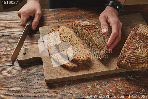 Image of Man slicing tasty fresh bread.