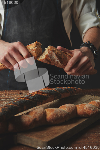 Image of Male hands break the baguette