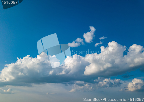 Image of White fluffy clouds in the blue sky at sunset in the summer day.