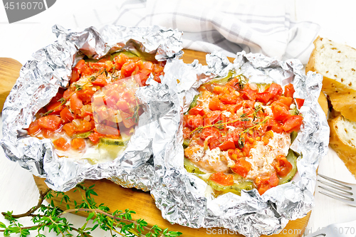 Image of Salmon with vegetables in foil on board