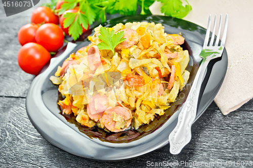 Image of Cabbage stew with sausages in plate on black board