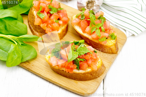 Image of Bruschetta with tomato and spinach on white wooden table
