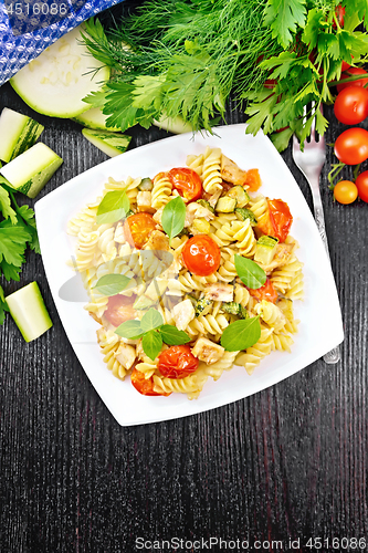 Image of Fusilli with chicken and tomatoes in plate on board top