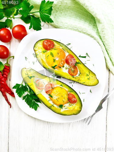 Image of Scrambled eggs with tomatoes in avocado on light board top