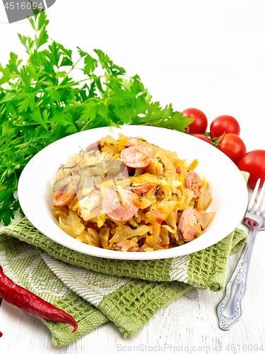 Image of Cabbage stew with sausages in plate on white board