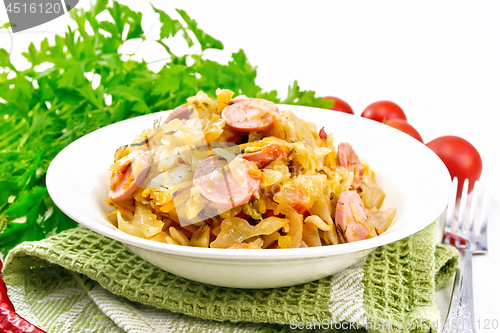 Image of Cabbage stew with sausages in white plate on table