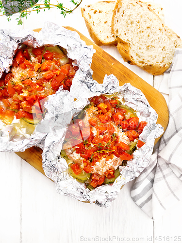 Image of Salmon with vegetables in foil on light board top