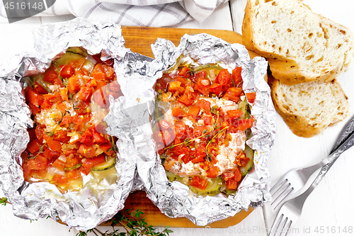 Image of Salmon with vegetables in foil on board top