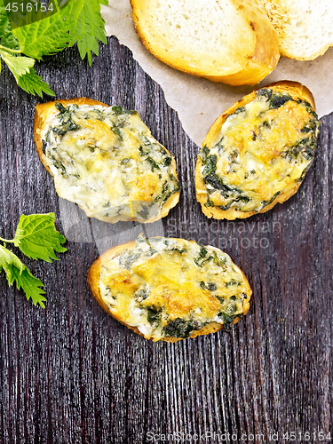 Image of Sandwich of nettle and cheese on dark wooden board top