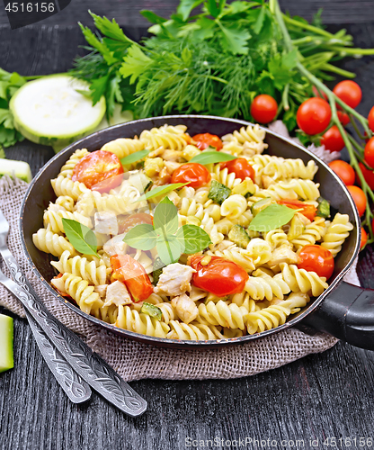 Image of Fusilli with chicken and tomatoes in pan on burlap