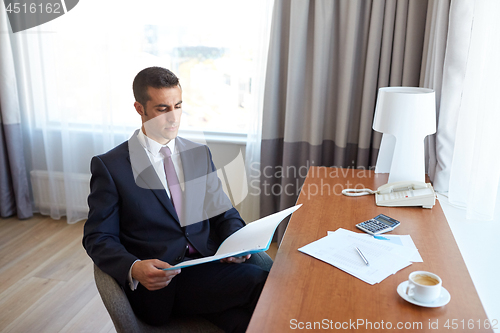 Image of businessman with papers working at hotel room