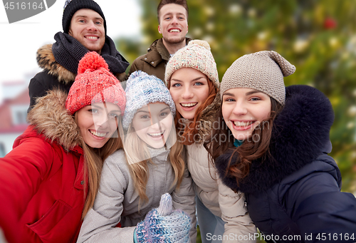 Image of friends showing thumbs up over christmas tree