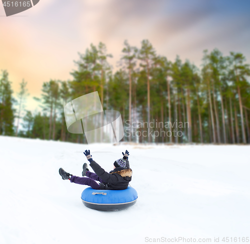 Image of happy young man sliding down hill on snow tube