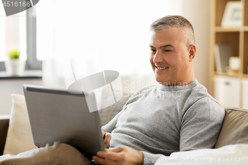 Image of man with laptop computer sitting on sofa at home