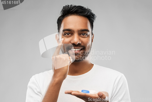 Image of young indian man applying contact lenses