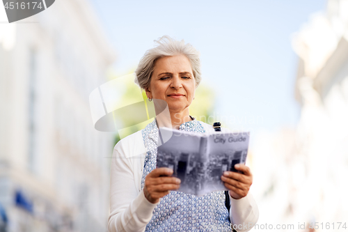 Image of senior woman or tourist with city guide on street