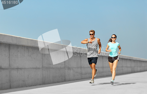 Image of couple in sports clothes running outdoors