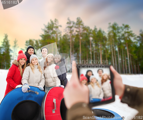 Image of friends with snow tubes taking photo by tablet pc