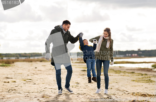 Image of happy family walking along autumn beach