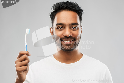 Image of indian man with toothbrush over gray background