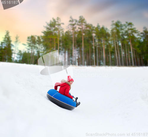 Image of happy teenage girl sliding down hill on snow tube