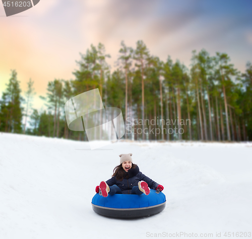 Image of happy teenage girl sliding down hill on snow tube