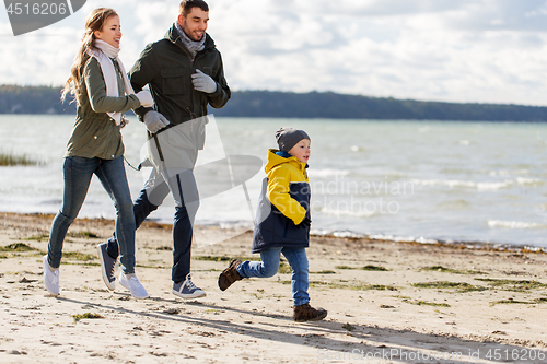 Image of happy family running along autumn beach