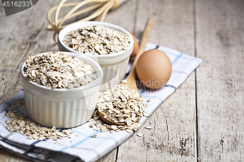 Image of Oat flakes in ceramic bowls and wooden spoon and fresh chicken e