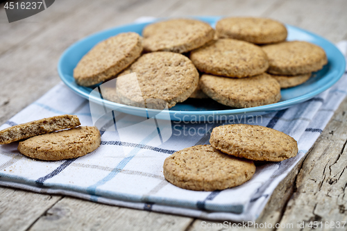 Image of Fresh baked oat cookies on blue ceramic plate on linen napkin on