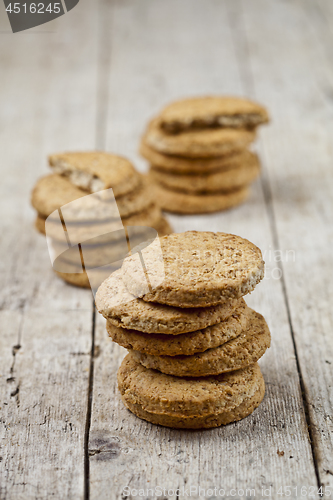 Image of Three stacks of fresh baked oat cookies on rustic wooden table.