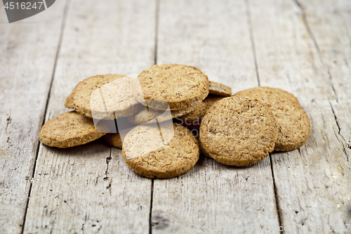 Image of Fresh baked oat cookies heap on rustic wooden table.