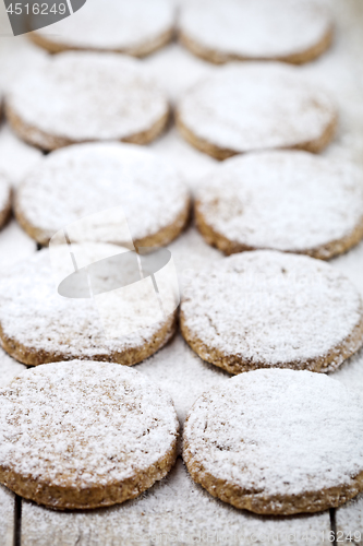 Image of Fresh baked oat cookies with sugar powder closeup on rustic wood