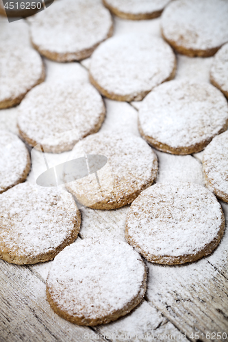 Image of Fresh baked oat cookies with sugar powder on rustic wooden table