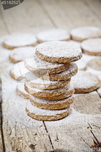 Image of Fresh oat cookies with sugar powder closeup on rustic wooden tab