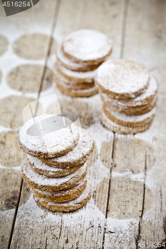 Image of Fresh oat cookies stacks with sugar powder on rustic wooden tabl