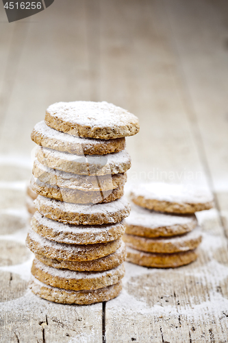 Image of Fresh oat cookies with sugar powder closeup on rustic wooden tab