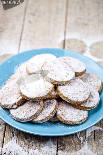 Image of Fresh baked oat cookies with sugar powderon blue ceramic plate o
