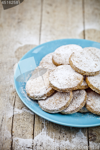 Image of Fresh baked oat cookies with sugar powderon blue ceramic plate c