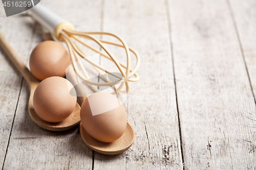 Image of Chicken eggs and kitchen utensil on rustic wooden table backgrou