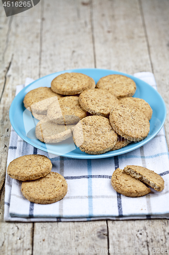 Image of Fresh baked oat cookies on blue ceramic plate on linen napkin on