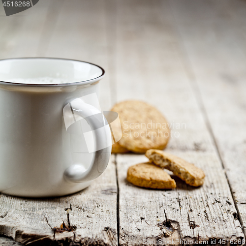 Image of Cup of fresh milk and some homemade baked oat cookies on rustic 