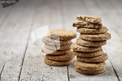 Image of Two stacks of fresh baked oat cookies on rustic wooden table bac